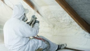 spray polyurethane foam for roof - technician spraying foam insulation using plural component gun for polyurethane foam, inside